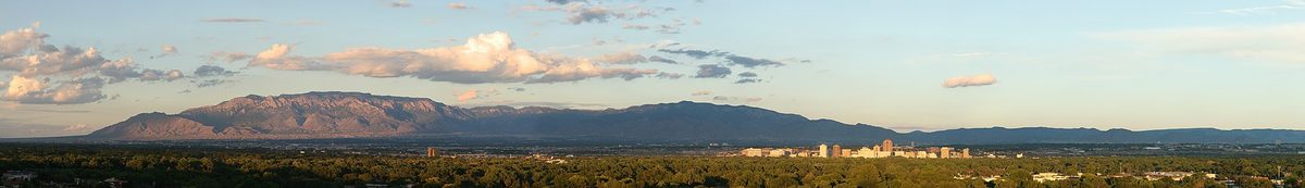 Albuquerque panorama at sunset with the Sandia Mountains rising behind the city.